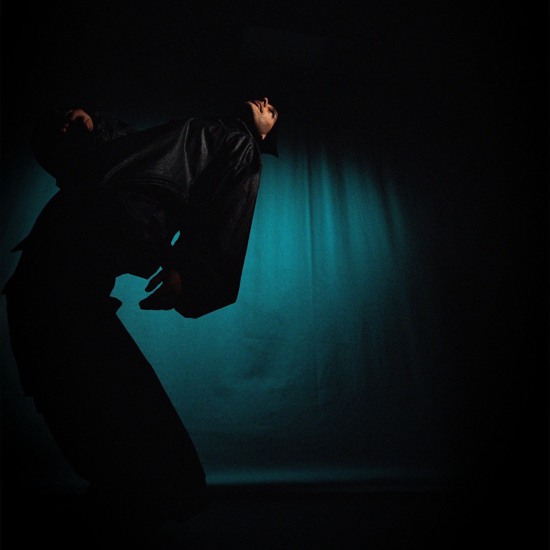 Chronis leaning back in teal stage light